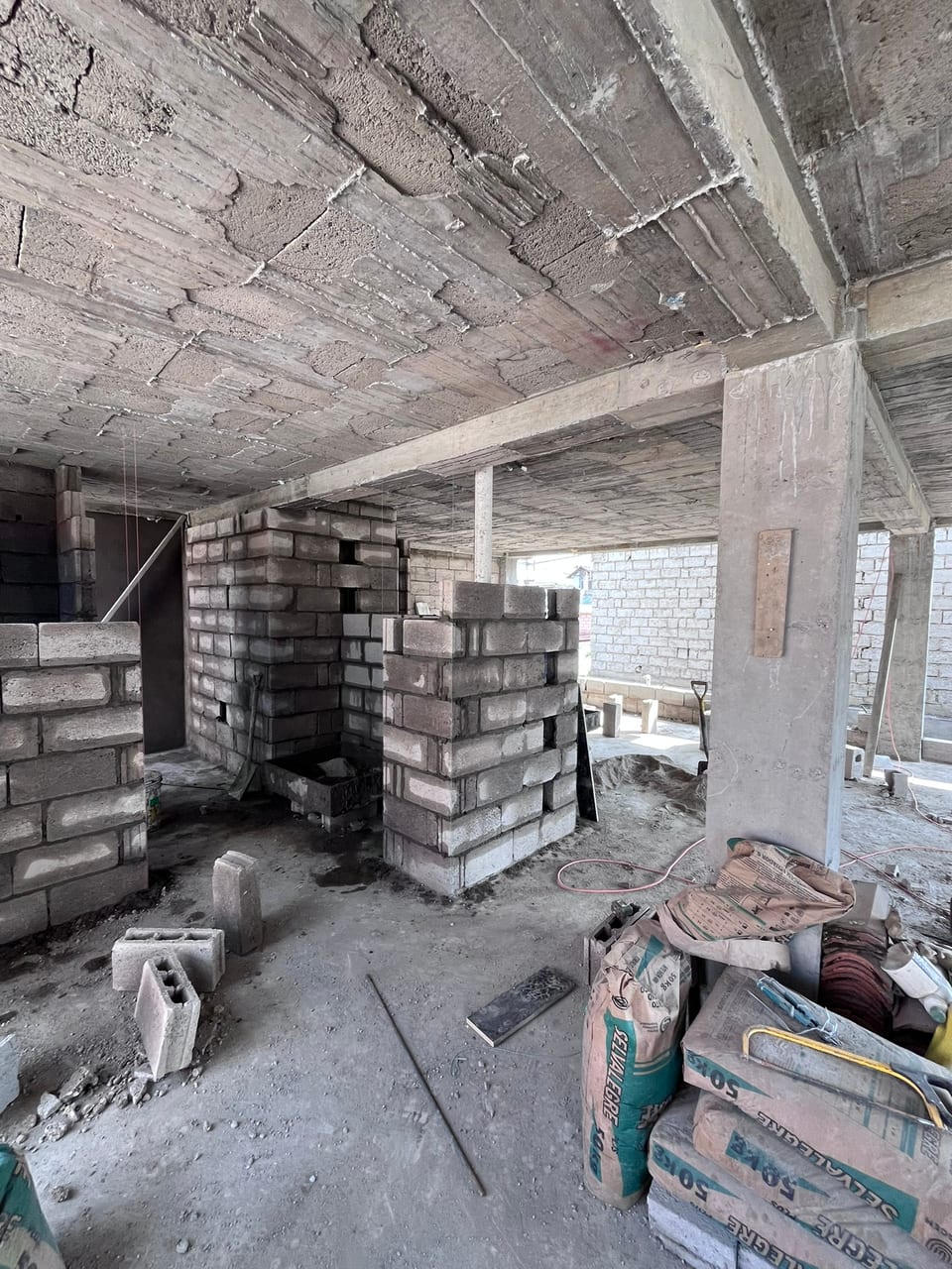 Interior en obra gris con losa nervada vista, columnas y mampostería de bloque